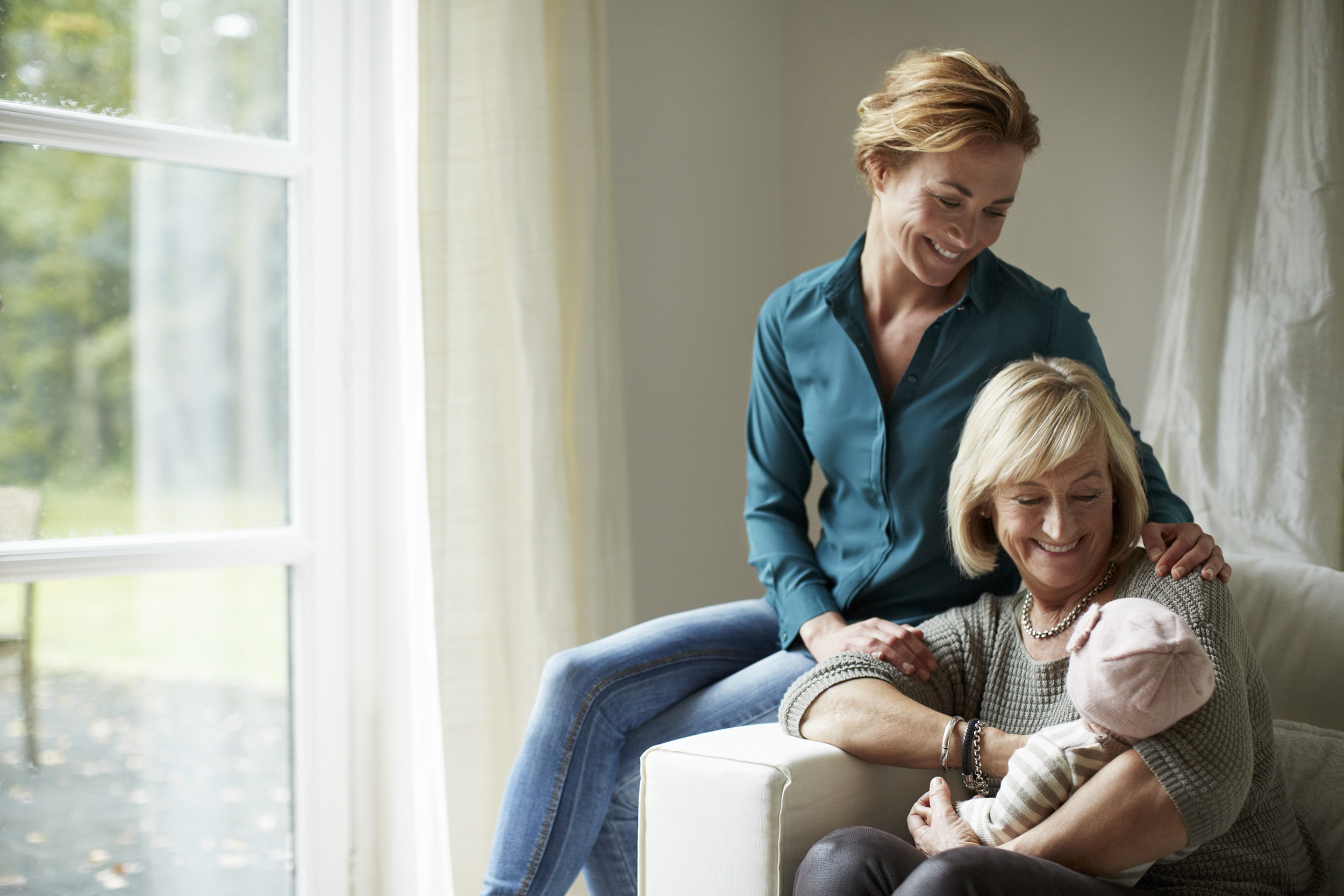 Person holding baby with another person sitting next to her