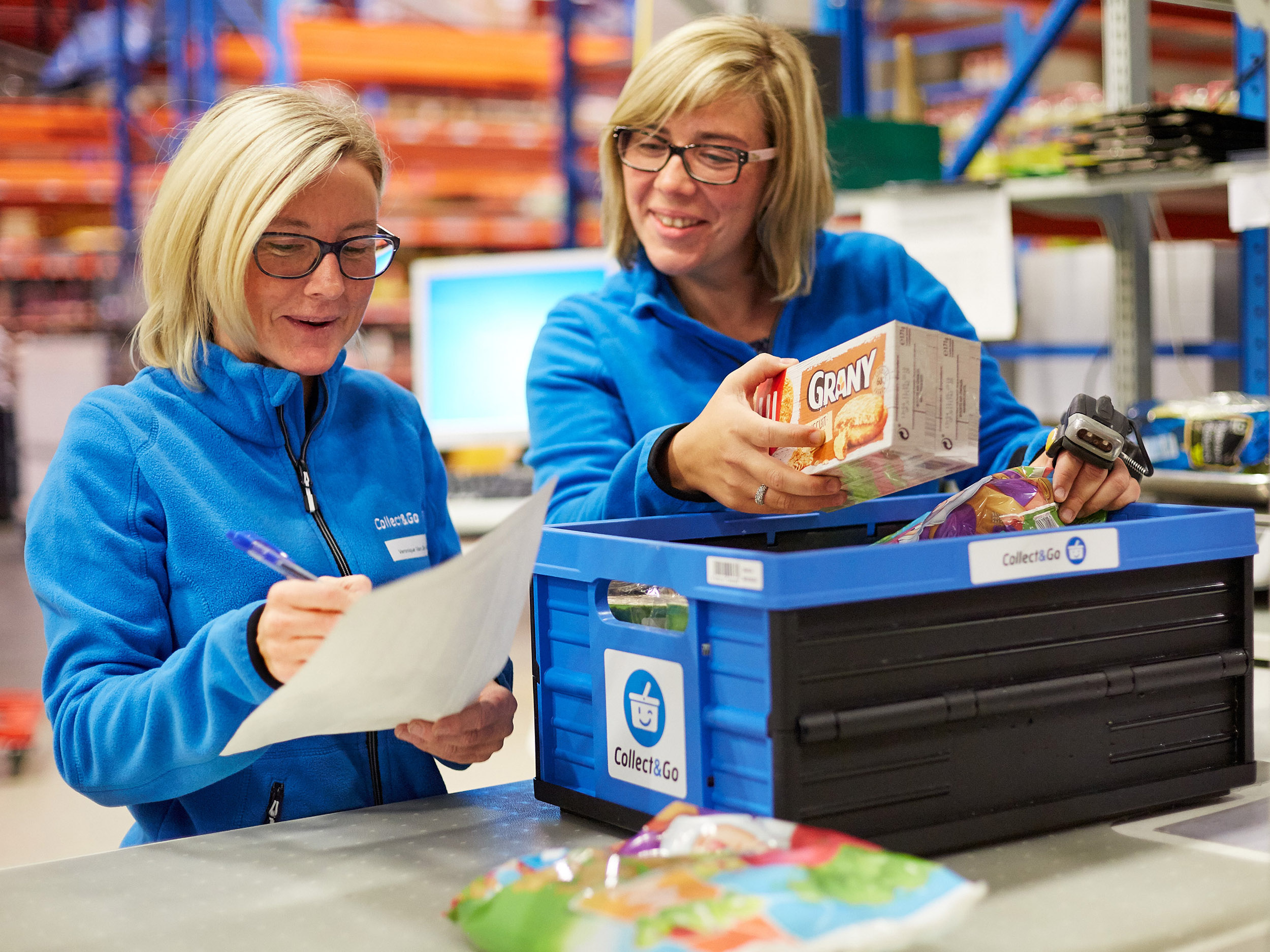 Collect&Go employees checking a list and filling a box with consumer goods 