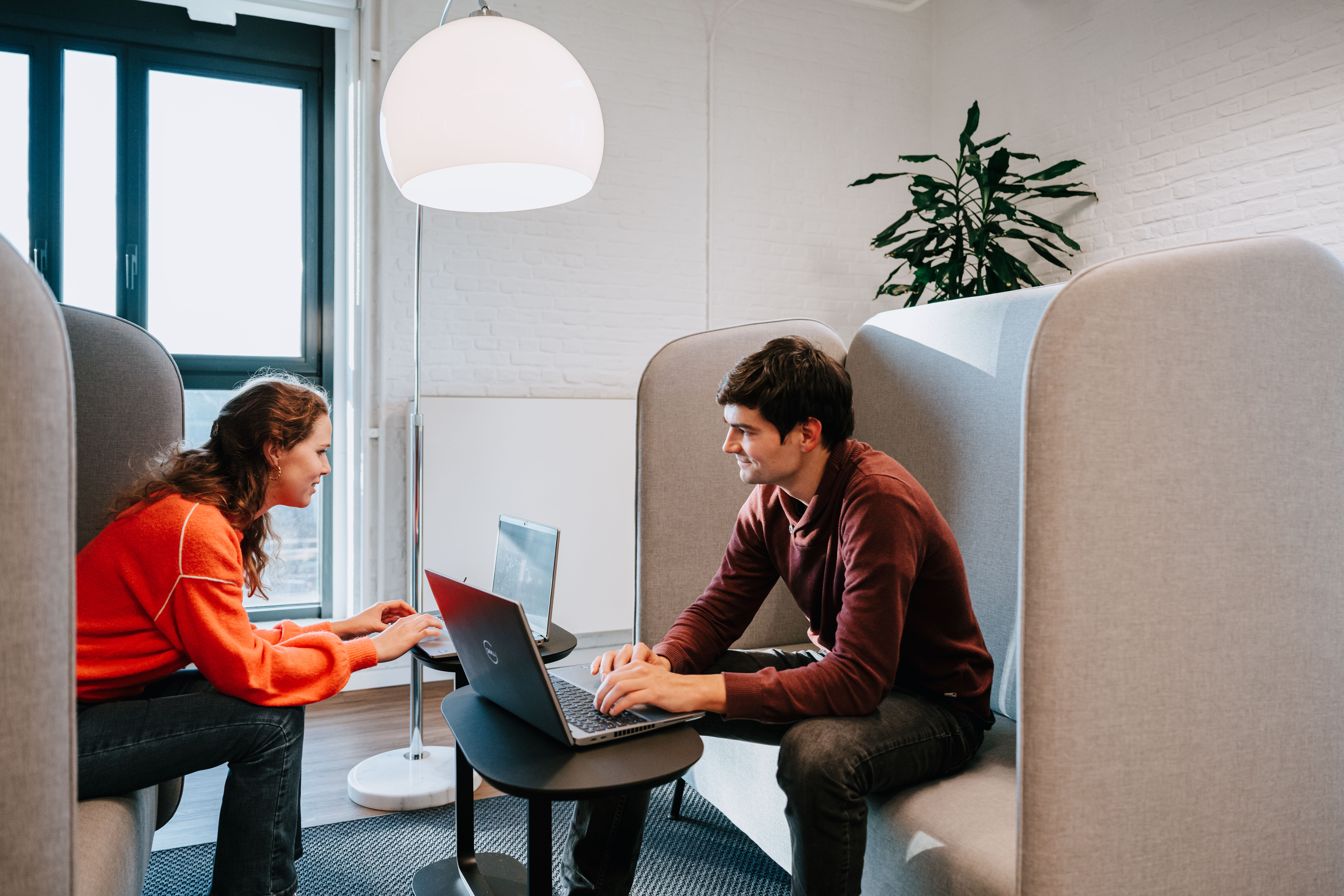 Two people sitting across from each other in a focused working booth