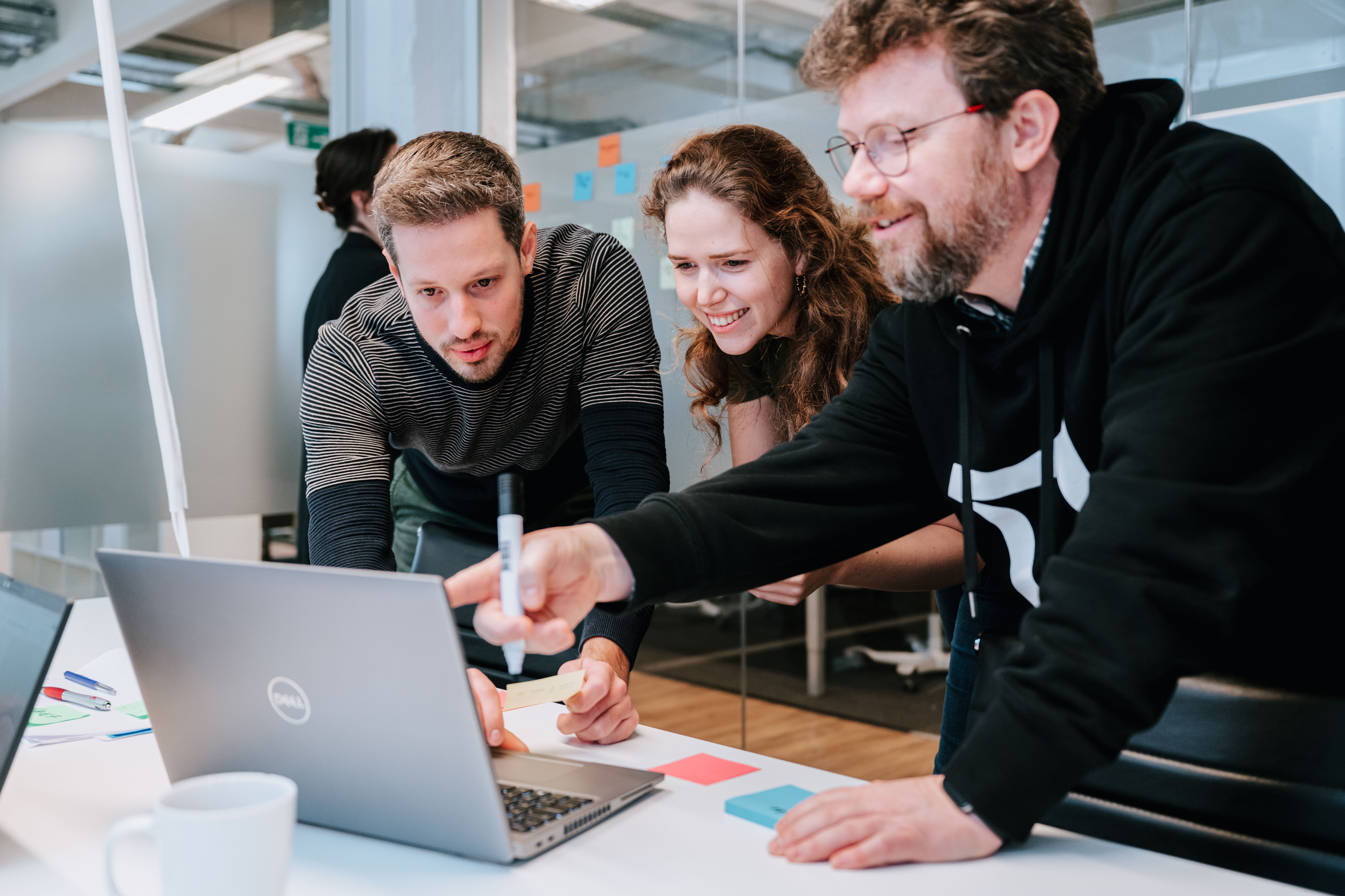 A person showing two colleagues something on a laptop 