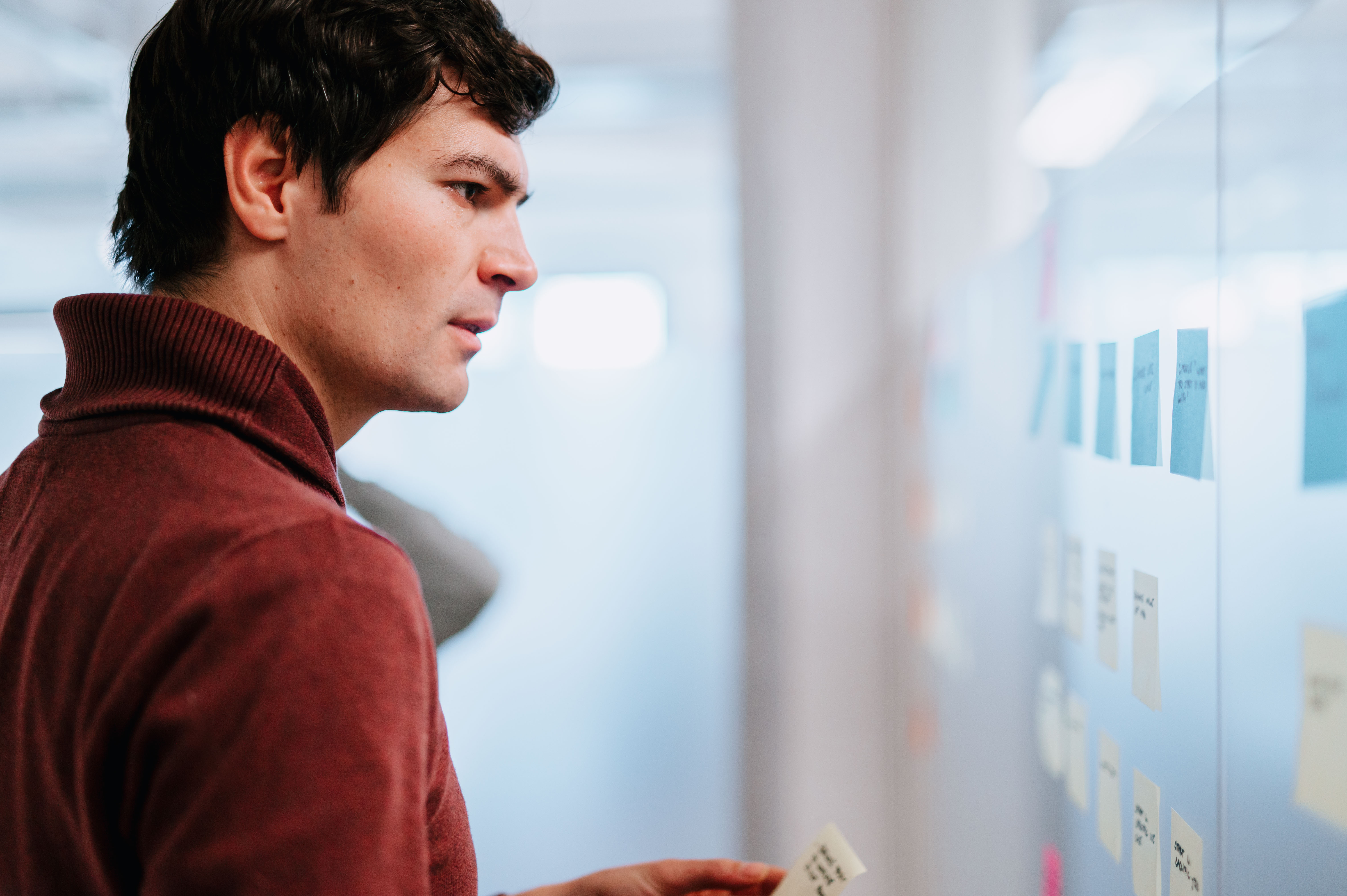 A person looking focused at the sticky notes on the wall