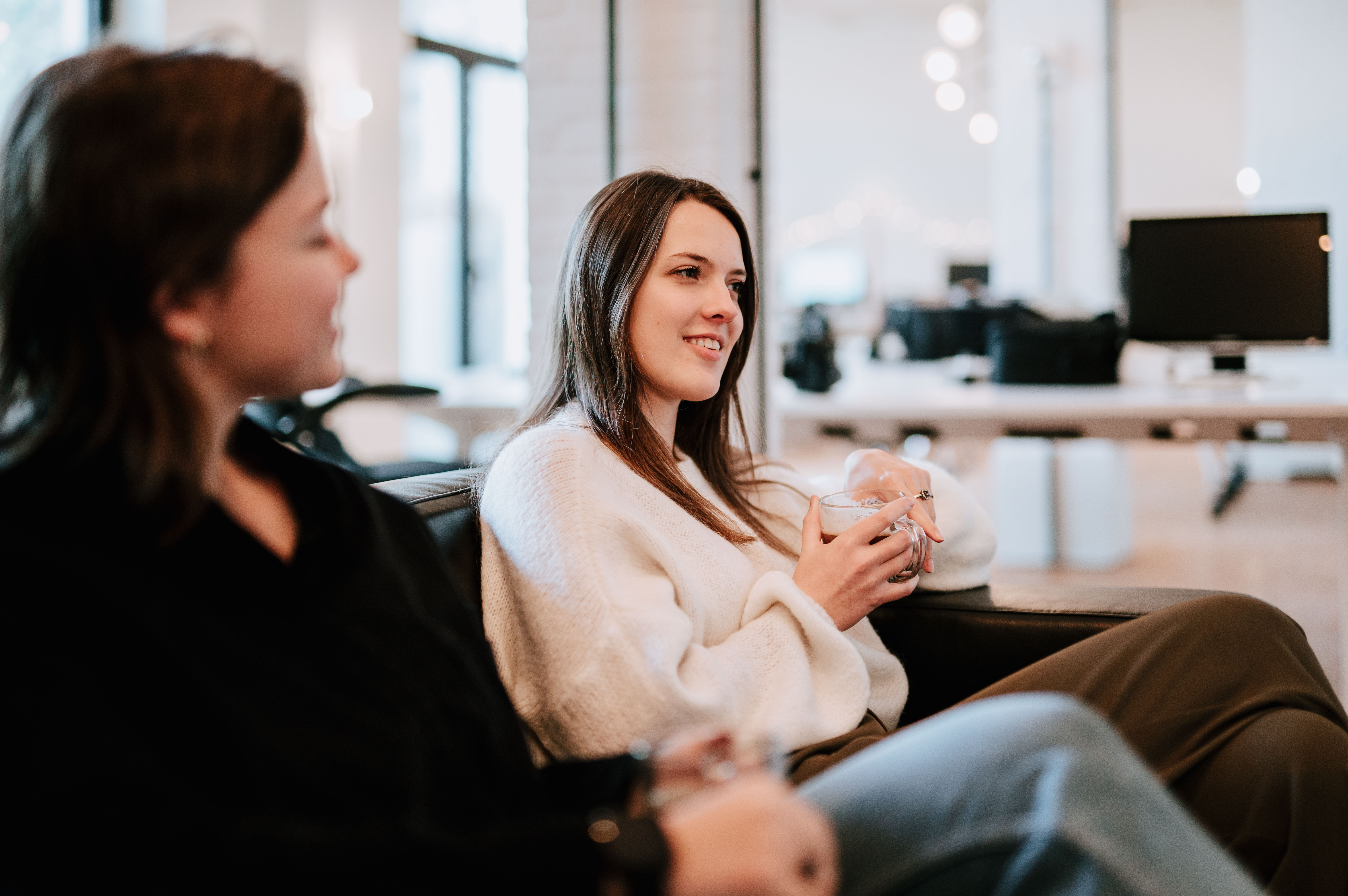 Two people sitting on a couch with one person holding a coffee mug