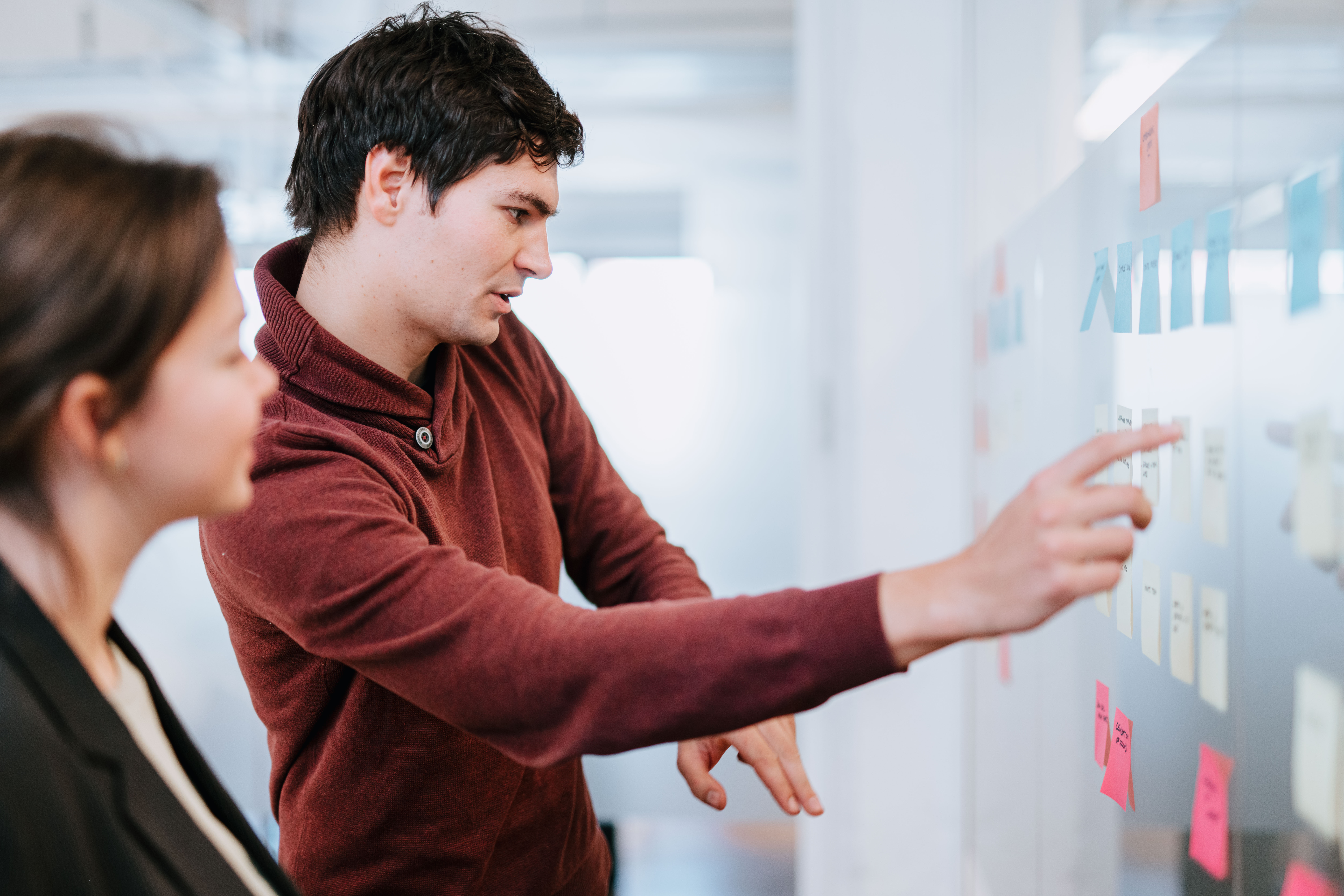 Two people discussing the post-its on the wall during a workshop