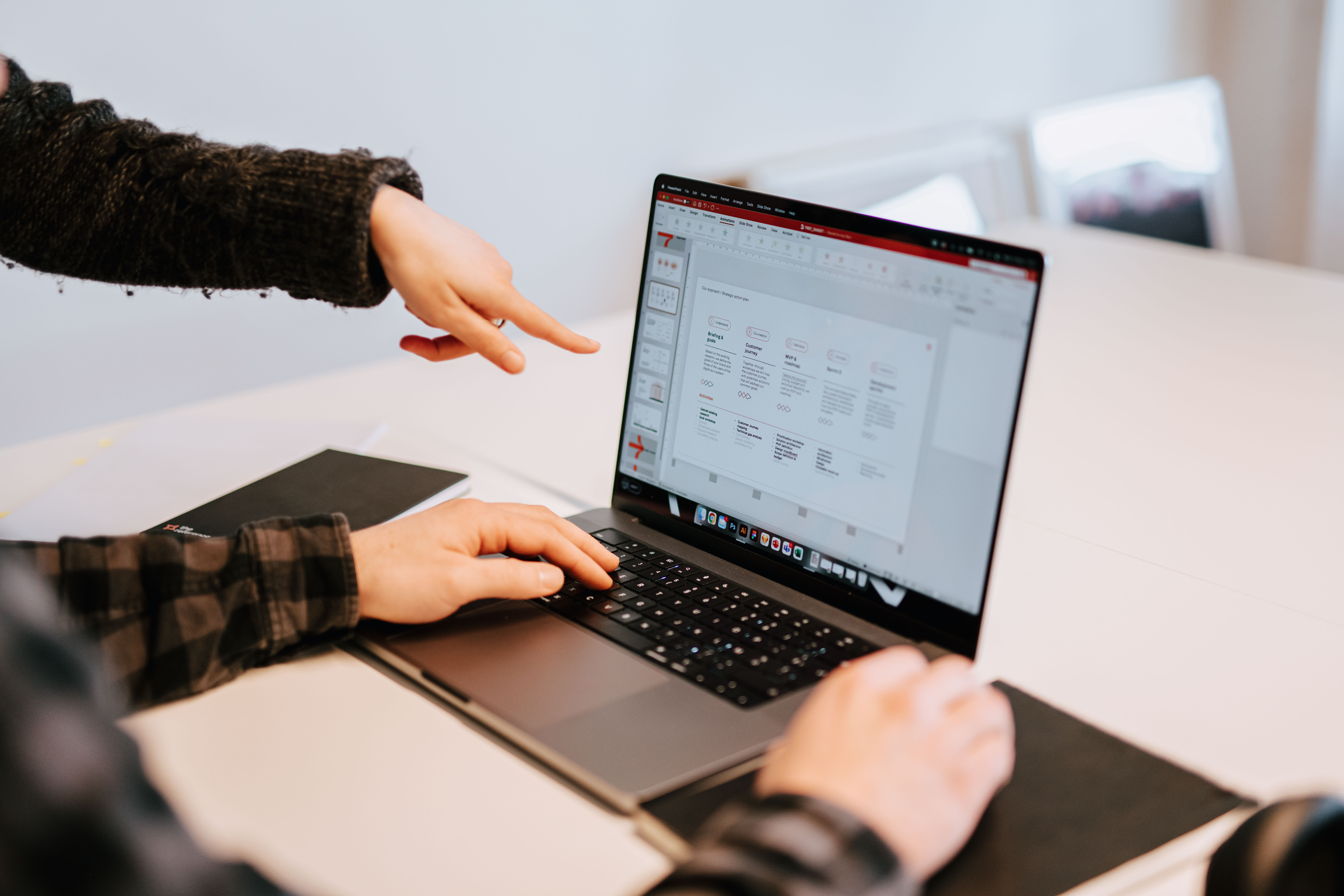 A person pointing at a laptop whit a PowerPoint on