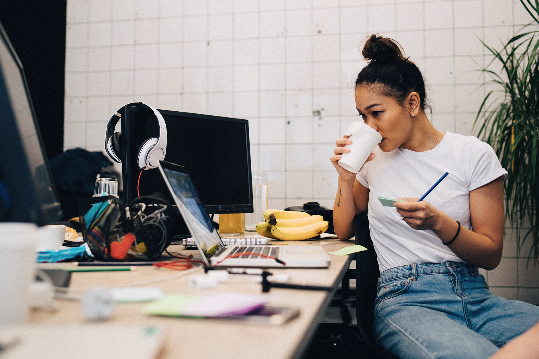 Person drinking from coffee sitting behind a desk 