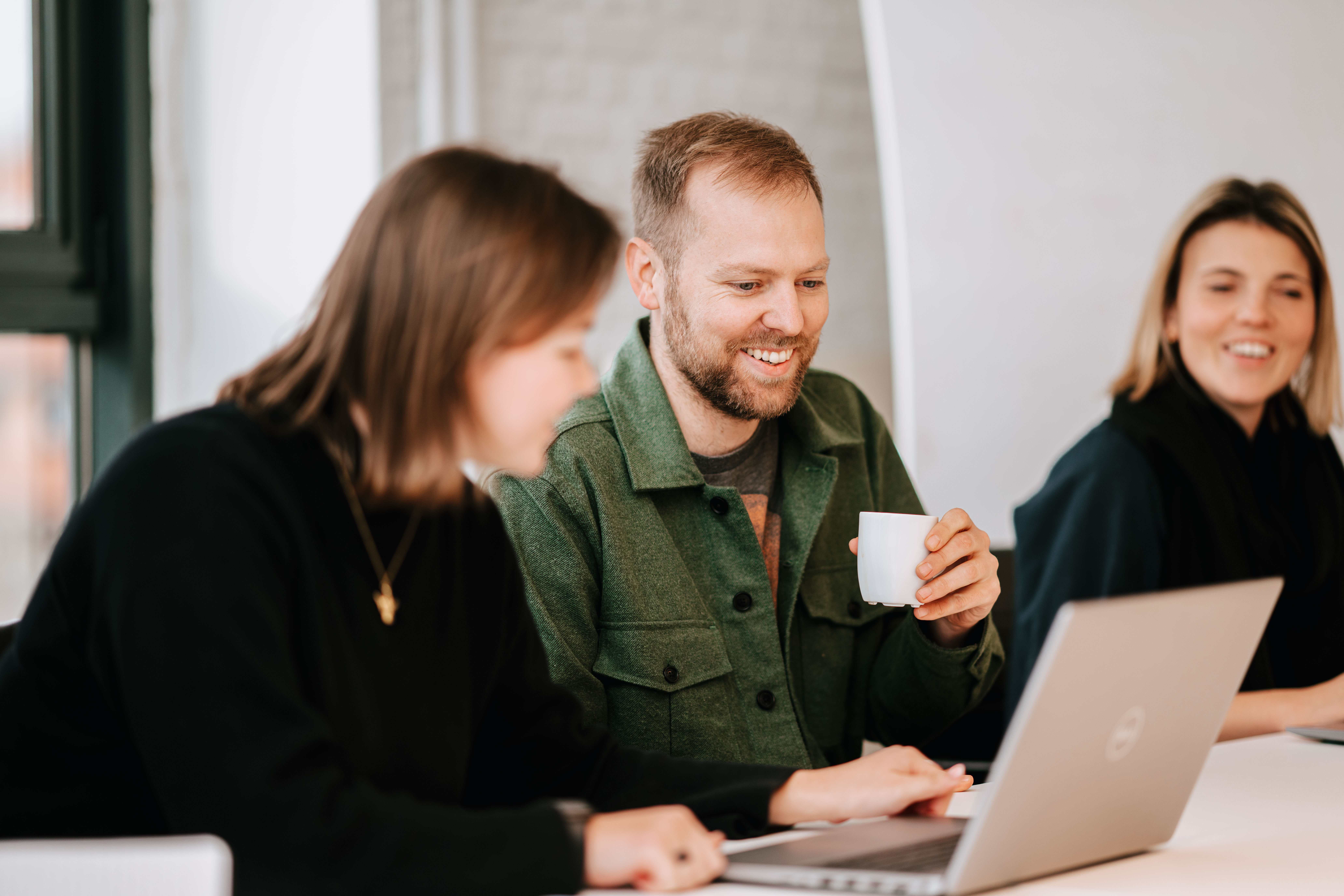 Three people in a meeting with a laptop