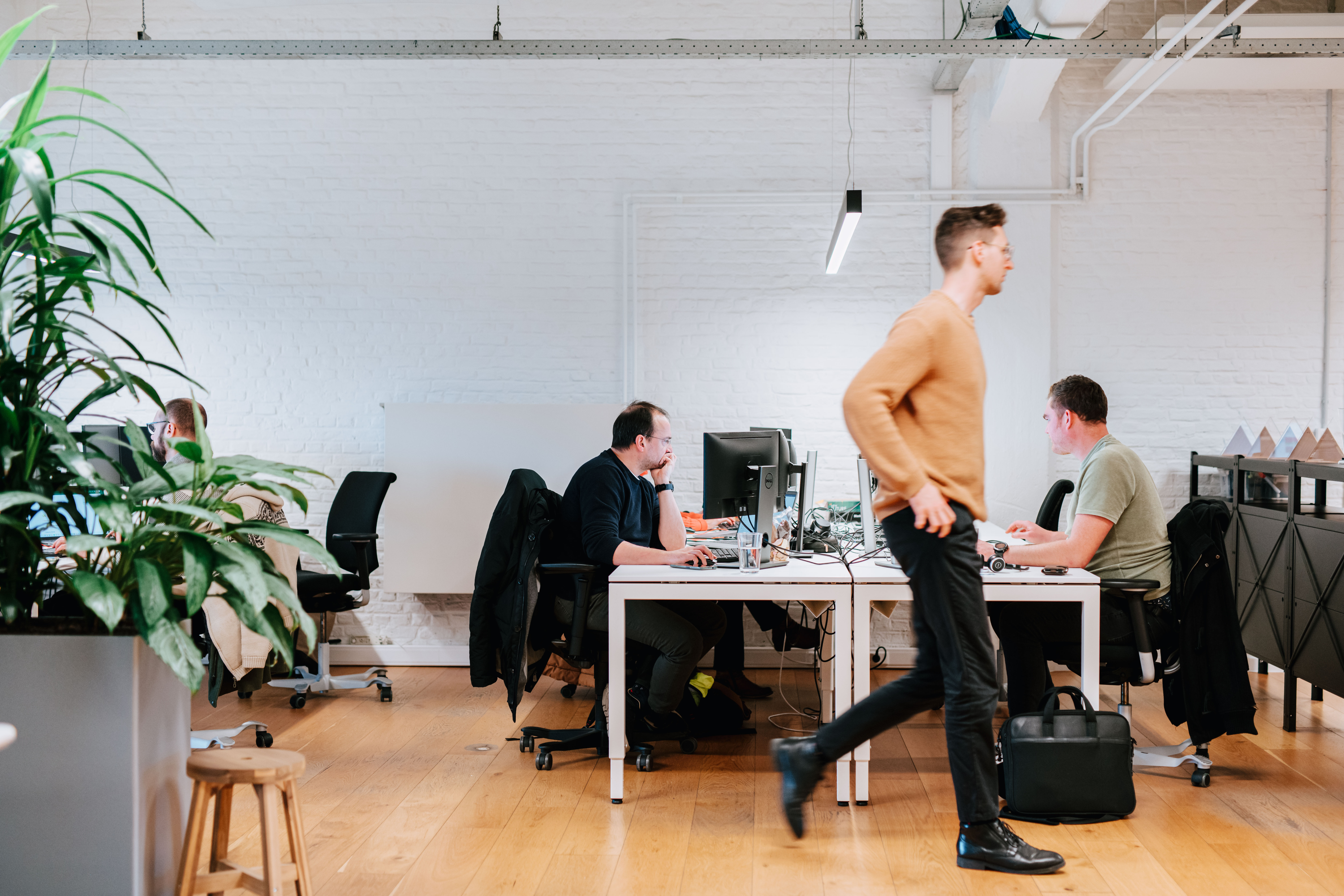 Wide shot of the office where people are working while someone passes