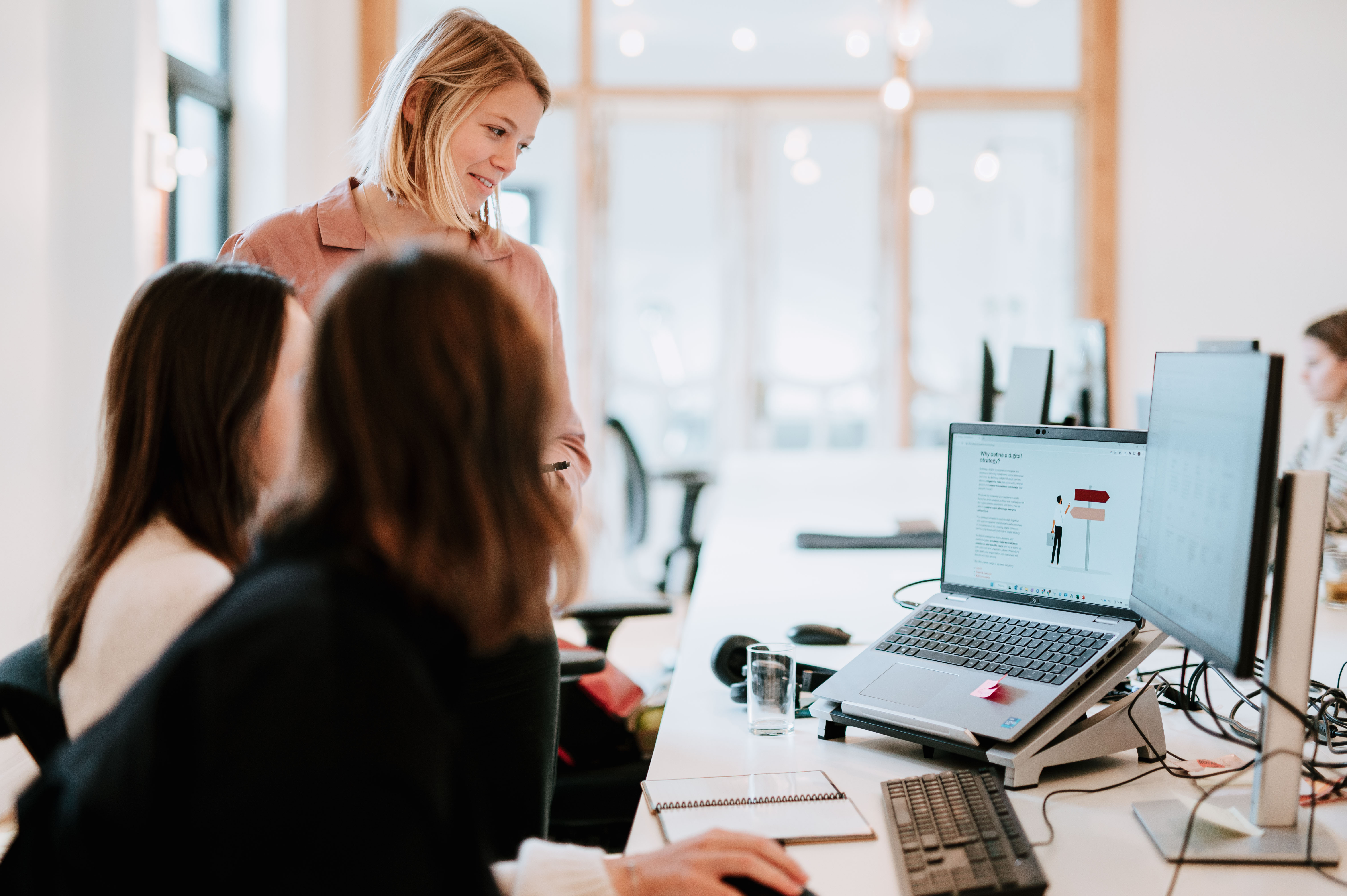 Three people behind a desk with one person focusing on a laptop screen